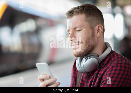 Mann am Bahnhof mit Handy auf Plattform Stockfoto