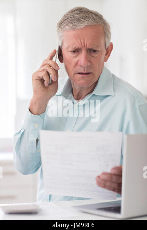 Unglücklich Senior Mann am Telefon Abfragen von Bill Stockfoto