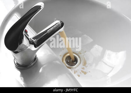 Wasserhahn Wasserhahn mit fließendem kontaminiert matschig und schmutziges Wasser in ein weißes Waschbecken. Stockfoto