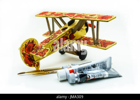 Spielzeugflugzeug gemalt in Chochloma Stil, Acrylfarben und Pinsel isoliert auf weißem Hintergrund Stockfoto