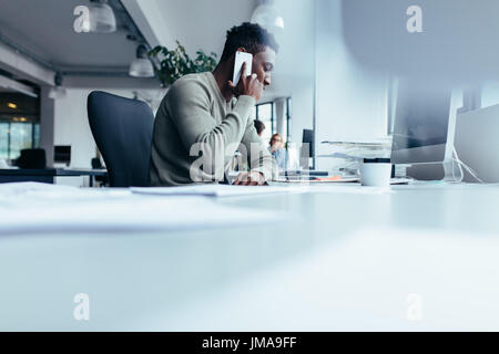 Afrikanischer Mann telefonieren mit Handy. Geschäftsmann, sitzen im modernen Büro mit Handy. Stockfoto