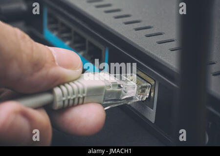 Person einstecken Kabel, WLAN-Router. Hautnah. Stockfoto