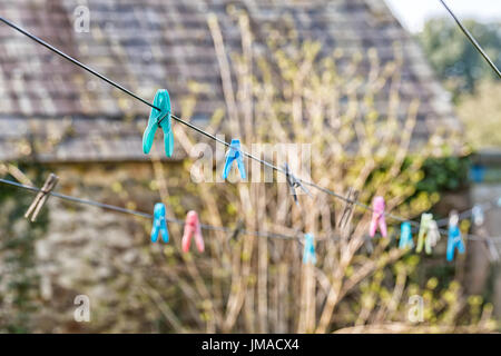 Bright farbigen Stöpsel auf eine Wäscheleine vor dem Hintergrund unscharf Baum Stockfoto