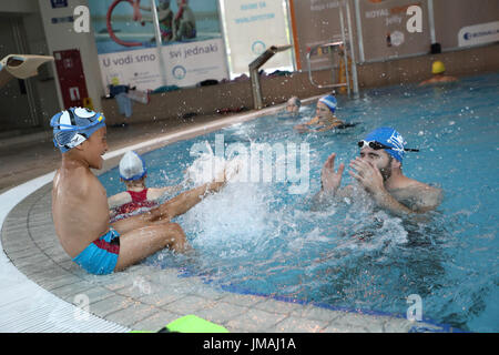 Sarajevo, Bosnien und Herzegowina. 25. Juli 2017. Behinderte junge spielt Ismail Zulfic (L) mit seinem Trainer in einem Schwimmbad in Sarajevo, Bosnien und Herzegowina, 25. Juli 2017. Ismail Zulfic begann, vor 18 Monaten schwimmen zu lernen. Er musste ganz von Zenica nach Sarajevo (70 km voneinander entfernt) zweimal in der Woche gehen die neue Fertigkeit erlernen. Bildnachweis: Haris Memija/Xinhua/Alamy Live-Nachrichten Stockfoto