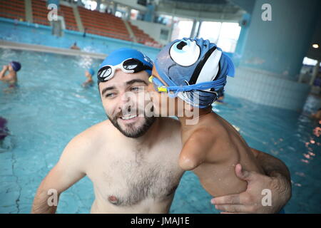 Sarajevo, Bosnien und Herzegowina. 25. Juli 2017. Behinderten jungen Ismail Zulfic (R) küsst seine Trainer in einem Schwimmbad in Sarajevo, Bosnien und Herzegowina, 25. Juli 2017. Ismail Zulfic begann, vor 18 Monaten schwimmen zu lernen. Er musste ganz von Zenica nach Sarajevo (70 km voneinander entfernt) zweimal in der Woche gehen die neue Fertigkeit erlernen. Bildnachweis: Haris Memija/Xinhua/Alamy Live-Nachrichten Stockfoto