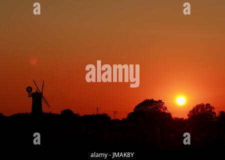 Große Bircham, UK. 25. Juli 2017. Der Himmel wird Orange, wenn die Sonne untergeht hinter Bircham Windmühle in Norfolk. Bircham Mill entstand im Jahre 1846, aber in den 1920er Jahren wurden die Segel entfernt und der Turm wurde aufgegeben, aber jetzt ist es eine vollständig restaurierte und Arbeitsbedingungen Mühle. Bircham Windmühle in großen Bircham, Norfolk am 25. Juli 2017 Credit: Paul Marriott/Alamy Live News Stockfoto