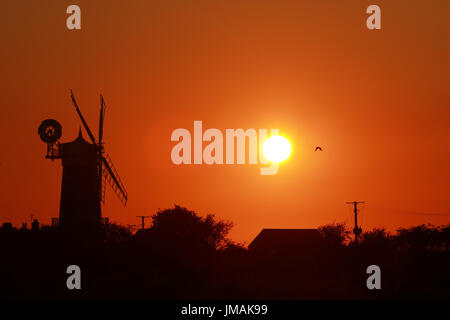 Große Bircham, UK. 25. Juli 2017. Der Himmel wird Orange, wenn die Sonne untergeht hinter Bircham Windmühle in Norfolk. Bircham Mill entstand im Jahre 1846, aber in den 1920er Jahren wurden die Segel entfernt und der Turm wurde aufgegeben, aber jetzt ist es eine vollständig restaurierte und Arbeitsbedingungen Mühle. Bircham Windmühle in großen Bircham, Norfolk am 25. Juli 2017 Credit: Paul Marriott/Alamy Live News Stockfoto