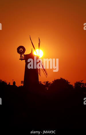 Große Bircham, UK. 25. Juli 2017. Der Himmel wird Orange, wenn die Sonne untergeht hinter Bircham Windmühle in Norfolk. Bircham Mill entstand im Jahre 1846, aber in den 1920er Jahren wurden die Segel entfernt und der Turm wurde aufgegeben, aber jetzt ist es eine vollständig restaurierte und Arbeitsbedingungen Mühle. Bircham Windmühle in großen Bircham, Norfolk am 25. Juli 2017 Credit: Paul Marriott/Alamy Live News Stockfoto