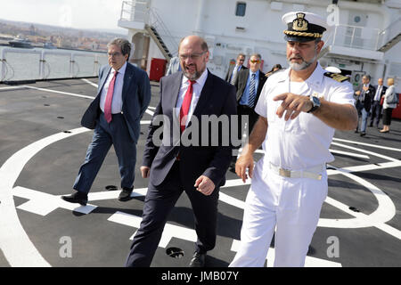 Catania, Italien. 27. Juli 2017. SPD-Kanzlerkandidat und Parteivorsitzende Martin Schulz (C) und Bürgermeister von Catania Enzo Bianco (L) besuchen eine italienische Küstenwache Schiff in den Hafen, wo Flüchtlinge in der mediterranen Ankunft in Catania, Italien, 27. Juli 2017 gerettet. Foto: Kay Nietfeld/Dpa/Alamy Live News Stockfoto