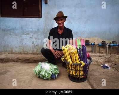ANTIPOLO CITY, Philippinen - 19. Juli 2017: Ein Mann aus Kunststoff Kleiderbügel auf einem Bürgersteig entlang einer Straße in Antipolo City verkauft. Stockfoto