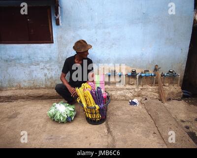 ANTIPOLO CITY, Philippinen - 19. Juli 2017: Ein Mann aus Kunststoff Kleiderbügel auf einem Bürgersteig entlang einer Straße in Antipolo City verkauft. Stockfoto