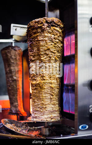 Traditionelle türkische Döner Kebap auf der Straße vorbereitet. Huhn und Rind Döner Kebap mit Feuer auf der Seite Stockfoto