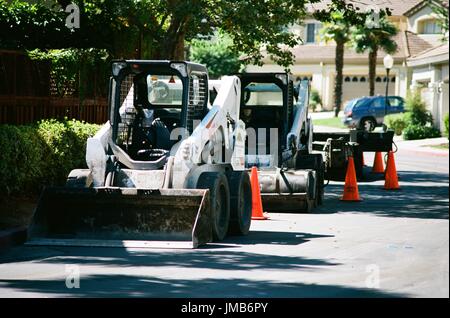 Eine Linie von front-End-Loader Baufahrzeugen ist neben einer Straße mit orange Leitkegel, während ein Straßenbau und resurfacing Projekt im Stadtteil San Francisco Bay Area von San Ramon, Kalifornien, 26. Juni 2017 geparkt. Stockfoto