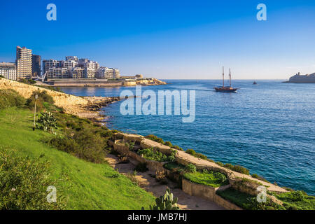 Valletta, Malta - Skyline-Blick auf Sliema bei Sonnenaufgang erschossen von Manoel Island im Frühjahr mit Segelboot, blauem Himmel und grünen Rasen Stockfoto