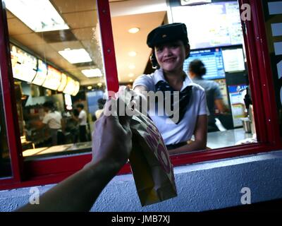 ANTIPOLO CITY, Philippinen - 17. Juli 2017: Ein Fast-Food-Kette-Arbeiter gibt ein Kunde ein gekauftes Produkt bei einer Fahrt durch. Stockfoto