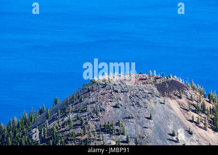 Der Rand des Wizard Island mit einer Spirale-Wanderweg an der Spitze gegen die schockierend blauen Wasser des Crater Lake National Park in Oregon. Stockfoto