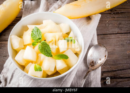 Sommerfrüchte. Veganes Essen. Schneiden Sie in Würfel schneiden, in eine Schüssel geben und Streifen vom Bio-Landwirt gelber Melone, auf einem rustikalen Holztisch. Kopieren Sie Raum Draufsicht Stockfoto