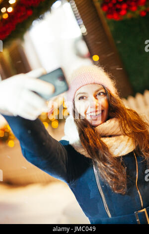 Energie-Füllung und aufregenden Winter-Wochenenden in den Bergen. Porträt der jungen Frau, die die Selfie im Freien zwischen schneebedeckten Bergen Stockfoto