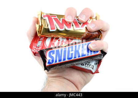 Eine Hand greift KitKat und Snickers, Twix Schokoriegel auf weißem Hintergrund isoliert. Stockfoto