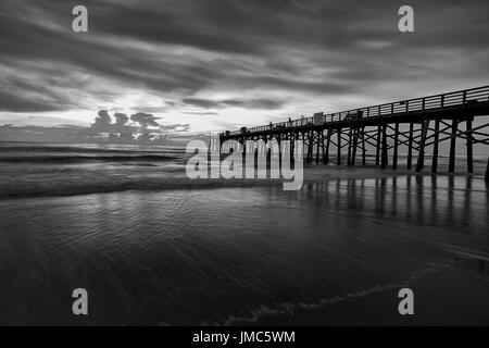 Ein B&W Bild der Sonnenaufgang über dem Atlantik am Pier in Flagler Beach, Florida. Stockfoto