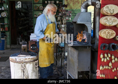 Cetinje, Montenegro - gealterte Schmied, Horseshoe Souvenirs und unterhaltsame Touristen in einer Straße workshop Stockfoto