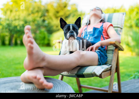 Hund und junges Mädchen im Garten Ruhe süß Boston Terrier Welpe auf dem Schoß seiner Dame Stockfoto