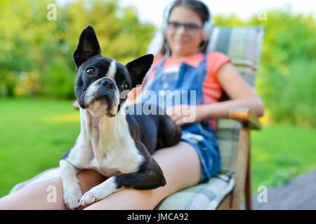 Hund und junges Mädchen im Garten Ruhe süß Boston Terrier Welpe auf dem Schoß seiner Dame Stockfoto