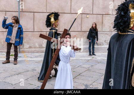 Little Boy tun Christi tragen ein Kreuz bei der Karfreitagsprozession, Ostern Feiern in der Stadt von Palermo, Sizilien, Italien Stockfoto