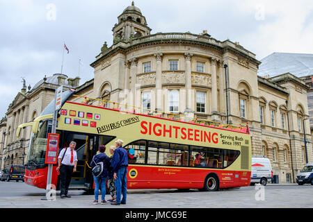 Ein Bad Stadt touristischen open Top Sightseeing Doppeldeckerbus ist abgebildet, wie es Touristen außerhalb Bath Abbey in Bath, Somerset, England, UK abholt Stockfoto