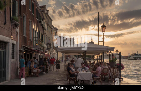 Speisen Sie wie die Sonne untergeht in ein Restaurant am Wasser auf der Insel Giudecca, Venedig, Italien. Stockfoto