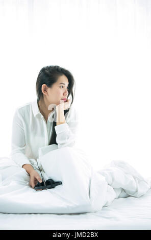 Asiatische Frauen mit Hand am Kinn und Musik hören. Nach dem Aufwachen am Morgen Wochenende in Relex und Entertainment-Konzept Stockfoto