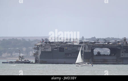 Ein Segelboot Pässe der US Navy Nimitz-Klasse-Flugzeugträger USS George H.W. Bush als es vor Anker aus der Coastbefore darin beteiligt sich n Übung sächsische Krieger 2017 im nördlichen Atlantik. Stockfoto