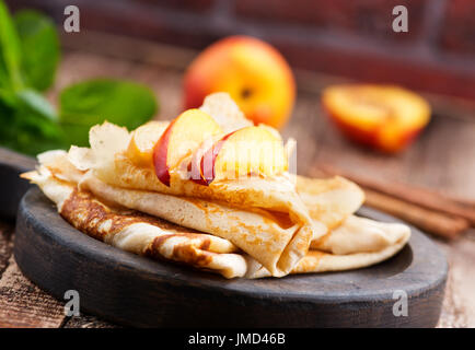 Pfannkuchen Sie mit Pfirsich und Zimt auf dem Holzbrett Stockfoto