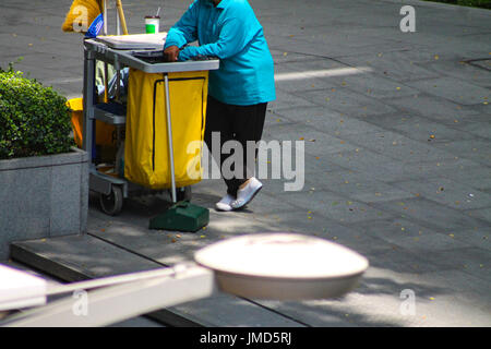 Ein Straßenreiniger macht eine Pause neben einem Mülleimer in Bangkok City, Thailand Stockfoto