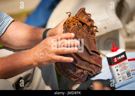 Ein Baseballspieler ölt seinen Handschuh mit Haushaltsöl, um ihn aufzuweichen und zu bewahren Stockfoto
