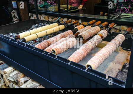 Trdelník, traditionelles Dessert gebacken in ein offenes Feuer Holzpfahl in Prag Weihnachtsmarkt, hergestellt aus gerollten Teig, der um einen Stock, th gewickelt wird Stockfoto