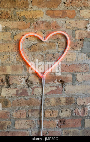Lichtschlauch auf Ziegelwand in Herzform Stockfoto