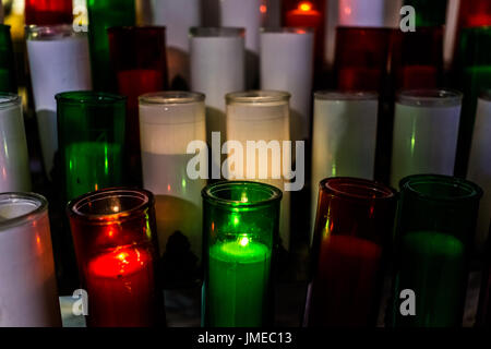 Makro Nahaufnahme von roten, grünen und weißen Kerzen mit gelben Flamme in der Kirche Stockfoto