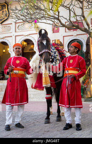 Marwari Pferde mit zwei Pfleger aufwendig dekoriert. Teilnehmer am Holi-Festival im City Palace, Udaipur, Indien Stockfoto