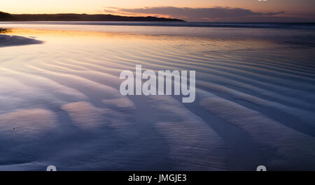 Sonnenaufgang über dem Sand bei Cave Beach in Booderee Nationalpark, NSW, Australien Stockfoto