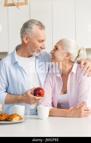 Foto des Lächelns Reifen liebenden paar Familie stehen in der Küche. Mann-Betrieb-Apfel. Mit Blick auf einander. Stockfoto