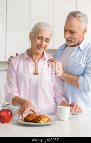 Bild glücklich Reifen liebenden paar Familie stehen in der Küche in der Nähe von Apfel und Gebäck. Auf der Suche zur Seite. Stockfoto
