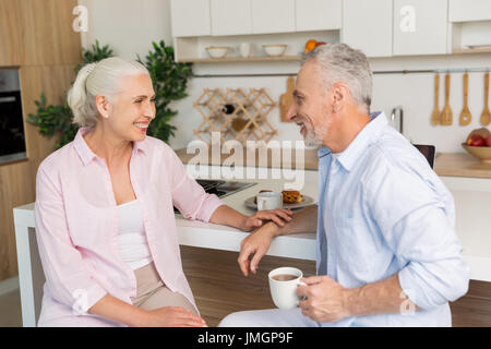 Bild der glückliche Reifen liebenden paar Familie sitzen in der Küche Tee zu trinken. Auf der Suche zur Seite. Stockfoto