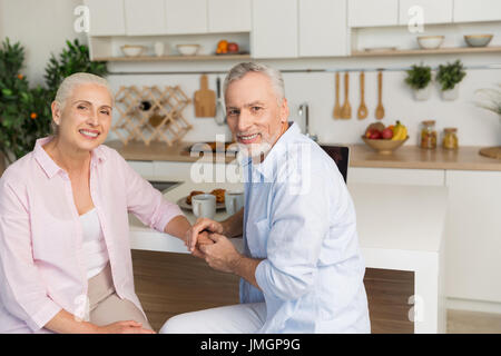 Bild von fröhlich Reifen liebenden paar Familie sitzen in der Küche. Blick in die Kamera. Stockfoto