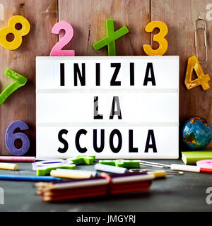 der Text Inizia la Scuola, zurück zur Schule in Italienisch, in einer Lightbox platziert vor einem rustikalen hölzernen Hintergrund, umgeben von dreidimensionalen Zahlen Stockfoto