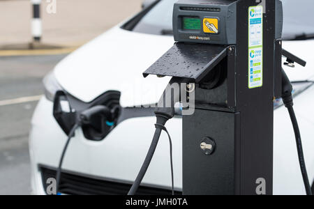 Ladestation mit einem kleinen Elektroauto EV eingesteckt beim Aufladen ihrer Batterien in Brighton, East Sussex, England, UK... Grünes Energiekonzept. Stockfoto