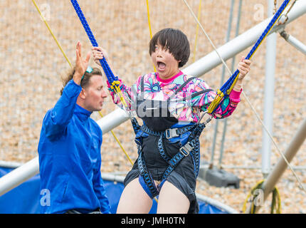 Junge japanische Mädchen lustig aufgeregte Gesicht machen, wie sie sich auf ein Bungee-Trampolin springen genießt. Bungee-Jump-Trampolin. Stockfoto