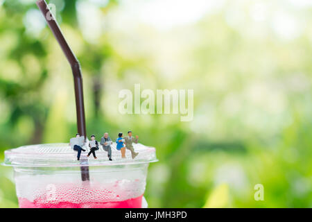 Miniatur Geschäftsmann und Business Mädchen sind ein Buch lesen und das Sitzen auf dem Plastik Tasse trinken, die Sie als Business und Bildung Konzept. Stockfoto