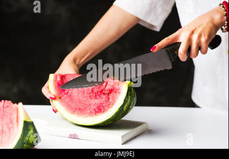 Frau, schneiden Wassermelone auf ein Schneidebrett Stockfoto