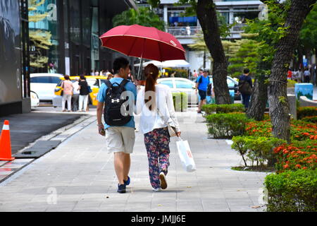 Ein Taiwan-paar, hält einen Regenschirm in der 90F-Grad-Wetter in Taipeh, Taiwan. Stockfoto